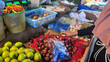 © color - Customer choosing fresh vegetables at traditional market stall with green tomatoes red onions and digital scale for local economy and daily life concept