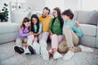 © deagreez - Happy family of five sitting together on the living room floor smiling and bonding while parents and children relax by the couch