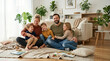 © Sali - Happy family of five sitting on the floor in a modern living room. Smiling parents with three children bonding at home. Caucasian mother and father with kids laughing together