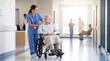 © Aurora Aesthetics - nurse pushing elderly patient wheelchair hospital corridor care medical support kindness mobility close up of female caregiver in blue scrubs assisting senior man through bright modern clinic hallway
