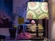 © Dmitry - Antique lamp with floral pattern shade illuminates pink retro rotary telephone and weathered hardcover books on table within atmospheric dimly lit interior setting