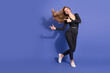 © deagreez - Young woman in striped jumpsuit dances against a violet background smiling and posing for a fashion image advertising fashion lifestyle and shopping campaigns