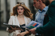 © qunica.com - A group of business people examine documents and a tablet while standing on a city sidewalk. Colleagues review reports together in an outdoor professional meeting.