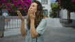 © Krakenimages.com - Woman wearing blue dress blows kiss with hands on street in front of white building facade; warm affection.