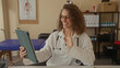 © Krakenimages.com - Woman doctor with stethoscope smiling and waving hand while holding tablet in building clinic exam room; compassion telemedicine.