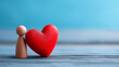 © Nataliya - Close-up of a red wooden heart and small human figure doll on a light blue background, health and care concept, mental wellbeing symbol, family and emotional support, with copy