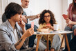 © standret - Group of young adults playing card games at a table with snacks and drinks, one person playing guitar in a cozy indoor setting with bright lighting