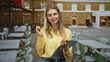 © Krakenimages.com - Blonde woman holding clipboard and pen, pen raised near lips at outdoor cafe in front of a building; calm contemplation.