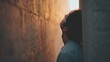 © koranis - A person leaning against a textured brick wall with a pensive expression, feeling loneliness