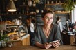 © Serhii - Female cafe owner uses a tablet at the counter in a cozy, welcoming cafe