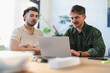 © Studio Marmellata - Two men collaborate on a project, looking at a laptop screen together in a bright, modern office setting.