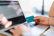 © Studio Marmellata - A person uses a credit card to make an online purchase on a laptop.