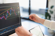 © Studio Marmellata - A person analyzes financial charts on a computer screen and a tablet, using a stylus to point at the data.