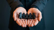 © cato_rium - Businessman holding black wooden human figures in palms. Concept of human resources, recruitment, talent selection, corporate team management and building successful business organization.
