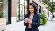 © AIPERA - Asian businesswoman using smartphone on urban street. Mobile technology, professional communication, and business success concept.