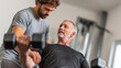 © Mike - Fitness trainer helps older man lift weights in gym during personal training session