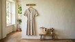 © ArtShop - Light linen dress hanging in bright room with wooden accents