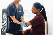 © Maskot - Female physical therapist examining arm of woman sitting in examination room at hospital