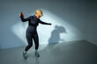© Maskot - Full length of happy senior woman dancing in front of wall