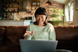 © Davor - Smiling woman video chatting on a laptop at home