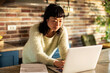 © Davor - Woman managing finances on laptop in home kitchen