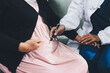 © Natchanida - Pregnant woman having her belly examined by a doctor with a stethoscope in a clinic room highlighting a medical checkup, pregnancy health, and prenatal care