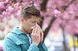 © New Africa - Man with paper tissue suffering from seasonal pollen allergy near blossoming tree on spring day, space for text