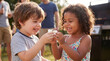 © Jian - Summer barbecue toddlers sharing marshmallow laughing together outdoors for joyful childhood friendship celebration party lifestyle photography