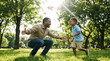 © Milan - Black father with open arms waiting for his son to run to him in the park. Happy African American dad and child playing outdoors. Father's Day concept
