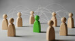 © Dudu - Networked Leadership: A Green Figure Standing Out Among Wooden Figures in a Social Connection Concept on a Gray Background