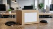 © Sonthana - A plain cardboard box with a blank label sits on a wooden desk, alongside a coiled USB cable and a wireless mouse in a modern office setting.