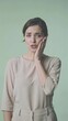 © clairelucia - A young woman has a toothache; the pain radiates to her left eye, against a pale green background, vertical