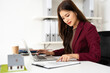 © Fahng - Focused female real estate agent reading and Reviewing contract document for real estate property purchase.