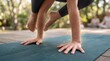 © Mudassar - Person practicing yoga outdoors on a green mat with hands and feet in a plank position on a sunny day