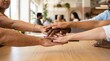 © Arief - Diverse team hands stacked together, unity and collaboration in modern office setting