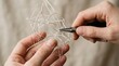 © mhmdyatt - Hands Creating Geometric Wire Art Sculpture on Neutral Background