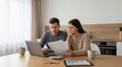 © Tonton1541 - first home buyer loan stress concept. Couple reviewing bills and finances at home with laptop and tablet.
