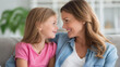© Nataliya - Close-up of a mother and daughter smiling at each other on a comfortable sofa, relaxed family lifestyle concept, mother daughter at home, warm relationship photography, defocused