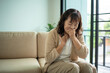 © Chanakon - Unhappy Asian senior woman coughing with illness and fatigue while sitting alone on living room sofa, healthcare and medical protection planning for life insurance in retirement age
