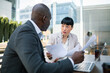 © Davor - Colleagues discussing documents at outdoor office terrace