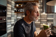 © Davor - Mature man enjoying green smoothie in home kitchen
