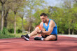 © Ljupco Smokovski - Man with injured knee sitting on a running track
