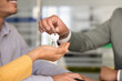 © fizkes - Closeup male manager, realtor agent handing house keys to couple during office meeting. Property purchase, successful real estate transaction, mortgage approval, home buying and deal closure concept