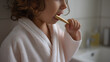 © photo for everything - Little Child in Robe Brush Teeth with Natural Wooden Toothbrush in Bathroom, Promote Oral Hygiene and Healthy Lifestyle for Kids