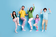 © deagreez - Happy family of five jumping and celebrating together on a colorful blue background, parents and children smiling in casual clothes expressing joy and togetherness