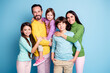© deagreez - Happy family portrait of parents and three children smiling together against a blue background, casual colorful clothing and warm affectionate multiage family moment