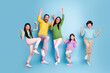 © deagreez - Happy jumping family of five with parents and three children celebrating together on a blue background, joyful colorful casual portrait showing playful energy and togetherness