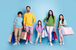 © deagreez - Happy family shopping together with colorful shopping bags — parents and children smiling in casual clothes against a blue background