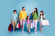 © deagreez - Happy family shopping together holding colorful shopping bags and walking smiling parents with children in casual pastel clothing against blue background