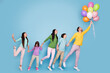 © deagreez - Happy family holding colorful balloons and walking together in a playful studio portrait with parents and children enjoying a joyful celebration